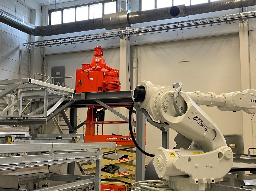 Nymonterad processmaskin på stålplattform bredvid en industrirobot i en industrihall.