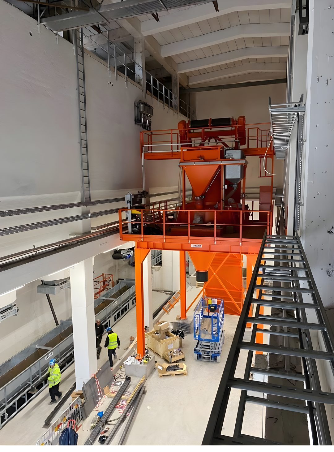 Tekniker från Dema utför montage av en stor stålkonstruktion inne i en industrihall.