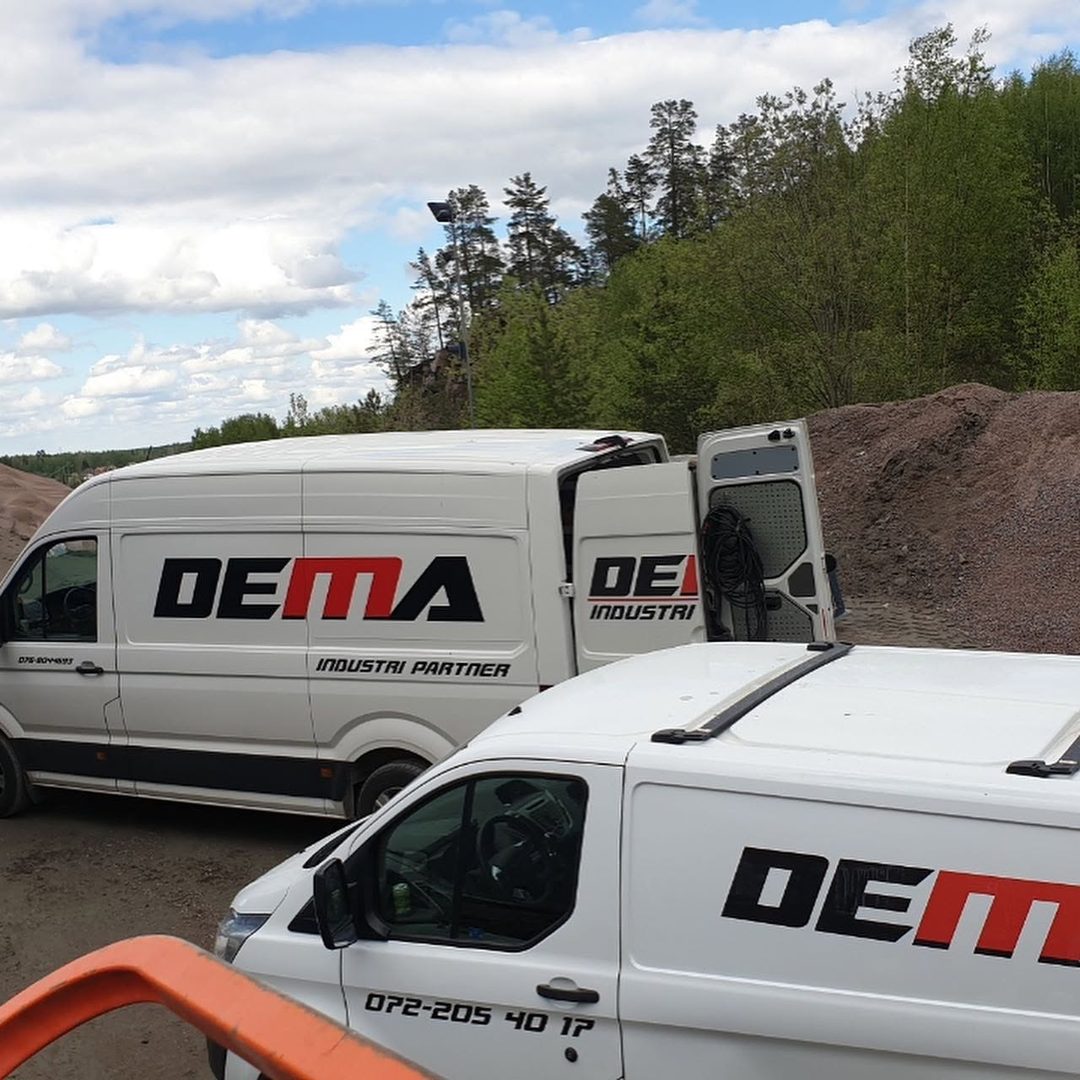 Två servicebilar från Dema Industripartner AB på plats vid en bergtäkt för industriservice i fält.